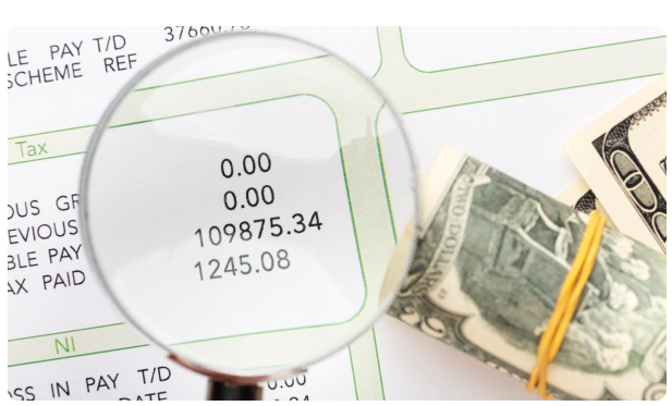 Magnifying glass over a payslip showing tax and net pay figures